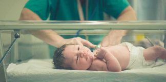 Mass Surrogacy Plot Hits Legal Wall Newborn baby in hospital bassinet being cared for by nurse
