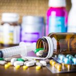 Offshore Gene Shot Promises Extra Years Medicine pills and syringe on table with brown bottle