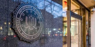 FBI emblem on a stone wall beside a glass entrance