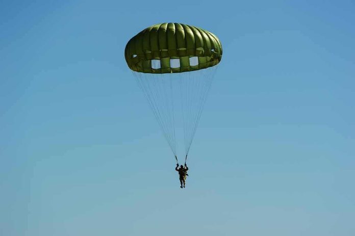 Parachutist descending under a green round canopy