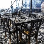 Burned dining tables and chairs in a fire-damaged building