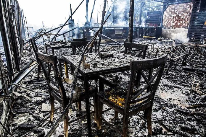 Burned dining tables and chairs in a fire-damaged building