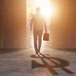 Businessman walking toward bright city doorway with briefcase