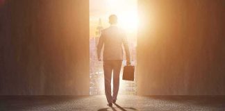 Businessman walking toward bright city doorway with briefcase