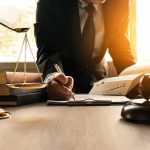 NFL Star’s Dark Trial Twist Lawyer writing at desk with scales and gavel
