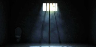 Shocking Move: American Walks Free Empty prison cell with light beams through a small barred window