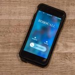 Smartphone on wooden surface showing an incoming robocall screen