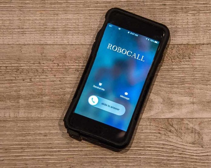 shutterstock_1228942621 Smartphone on wooden surface showing an incoming robocall screen