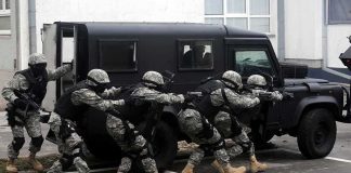 Tactical team advances beside an armored vehicle
