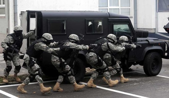 Tactical team advances beside an armored vehicle