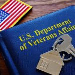 VA folder with house keychain and US flag patch on wooden desk