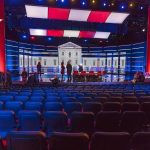 Tight Race, Candidate Disappears Debate stage with red and blue lighting and empty audience seats