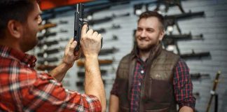 man examining a handgun at a gun store counter