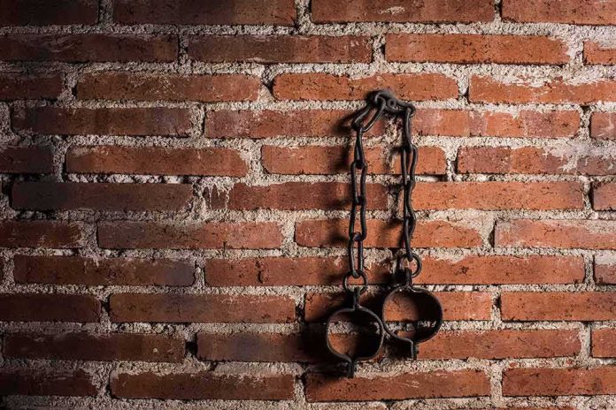 shutterstock_1696629445 Iron shackles hanging on a brick wall