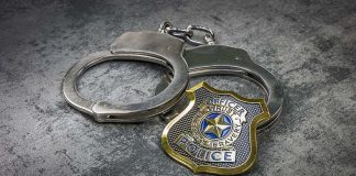 Handcuffs and police badge on a gray surface