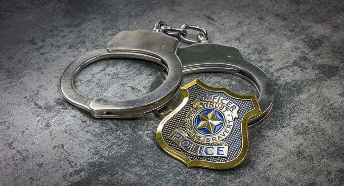 Handcuffs and police badge on a gray surface