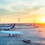 Airplanes on airport tarmac at sunset