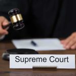 Judge with gavel and Supreme Court nameplate